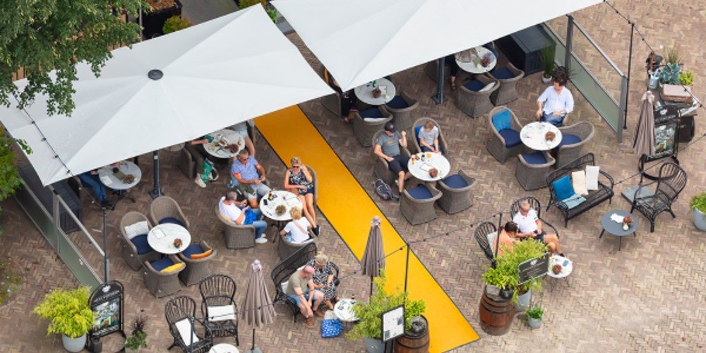 Terras met tafels, mensen en parasols van bovenaf gezien